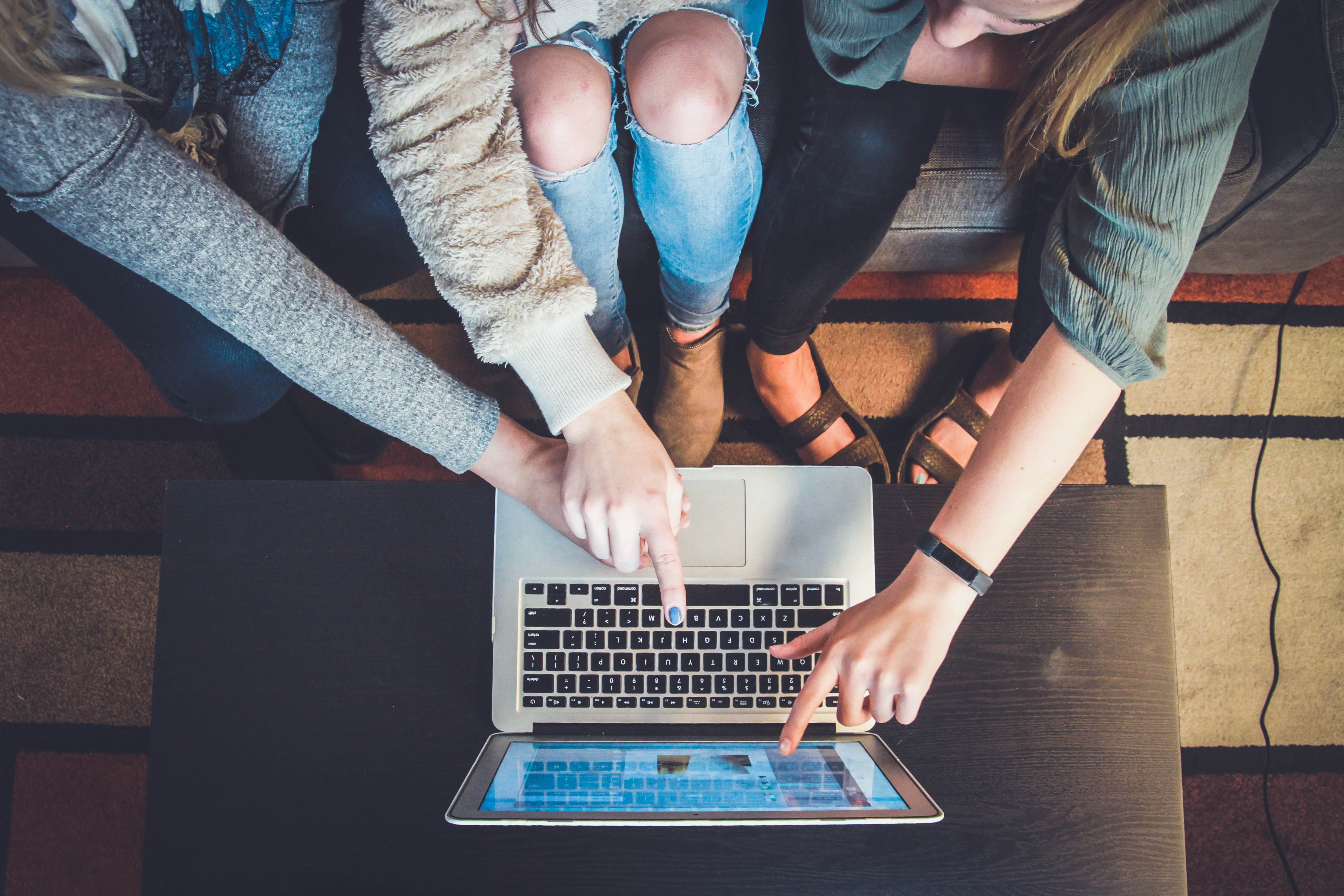 Three people sat pointing at a computer screen